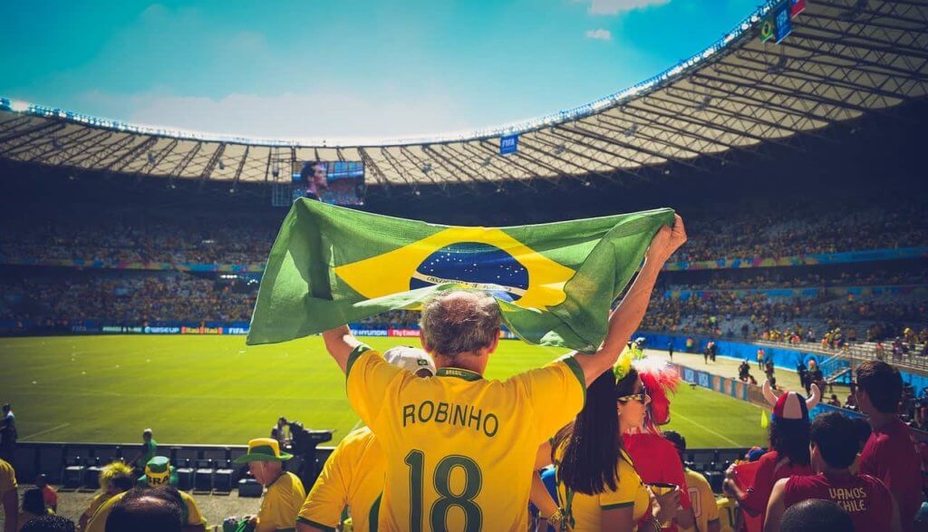 A soccer fan holds a brazilian flag over his head during a match