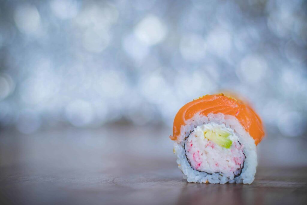 A single sushi piece with salmon on a table.
