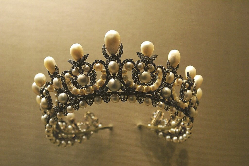 A crown made of pearls sticks out of a cork wall
