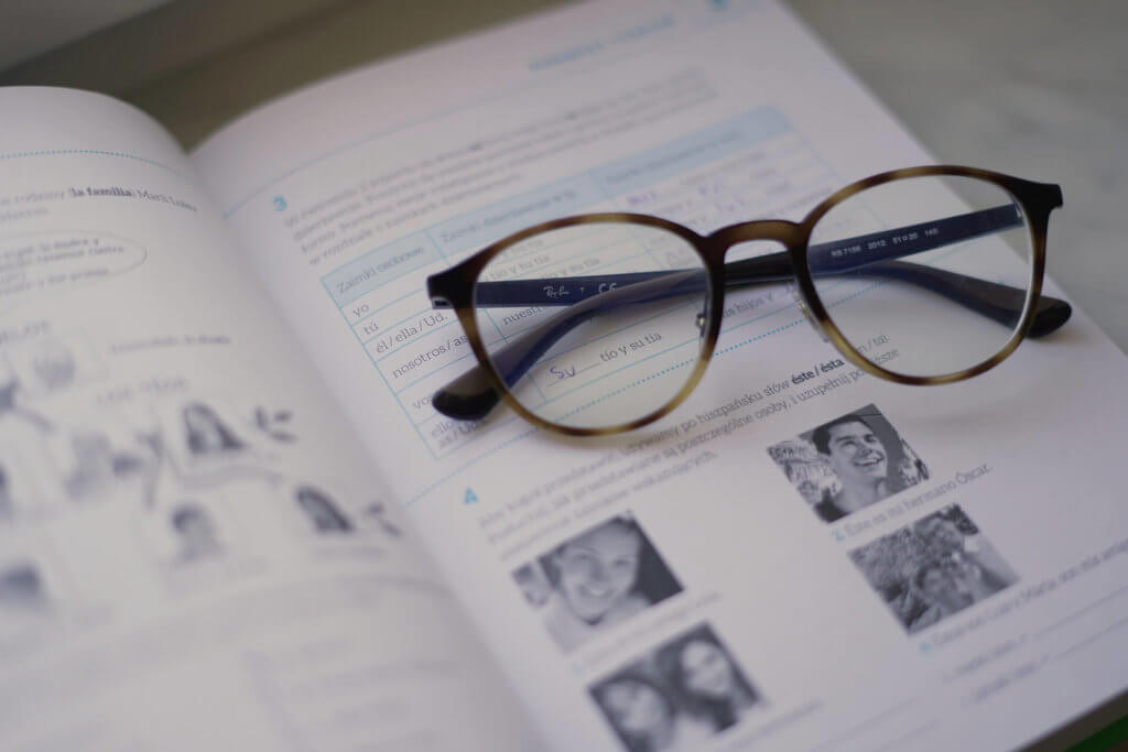 A pair of reading glasses lying on top of a Spanish grammar book.