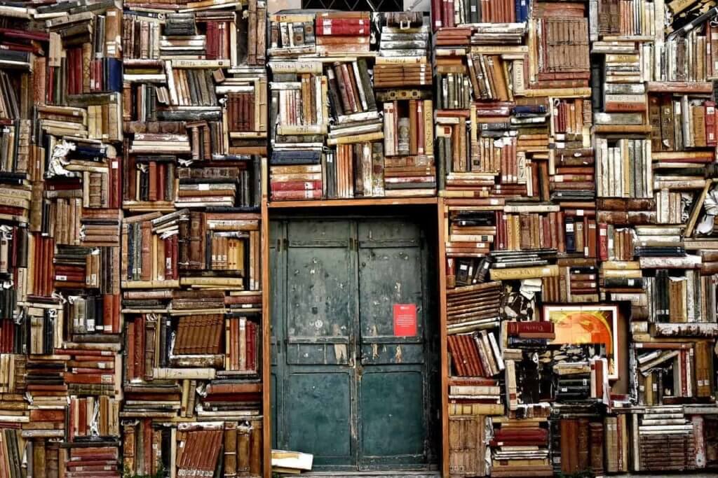 A door surrounded by stacked wall of books