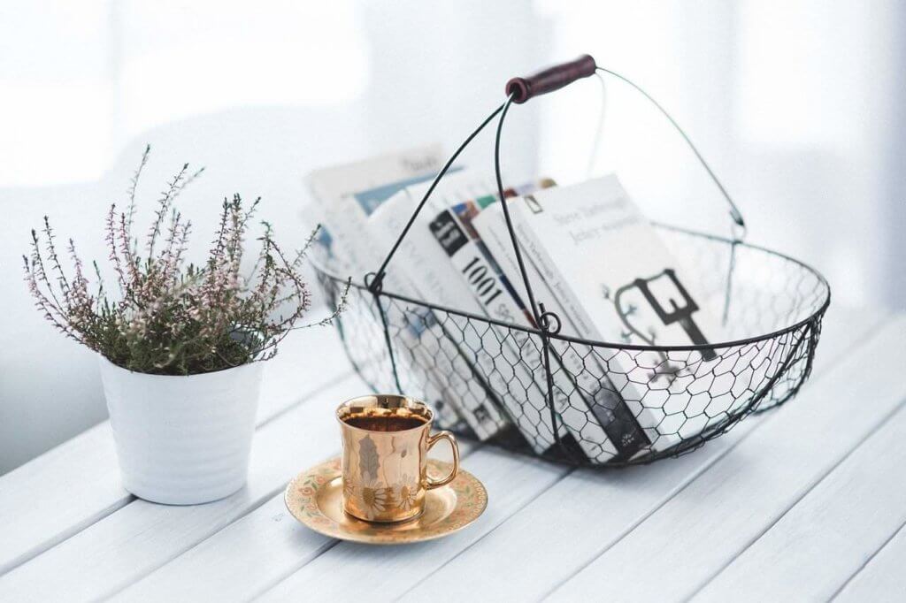 A golden espresso cup sits next to a wire basket with books in it