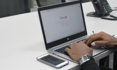 hands typing on a laptop keyboard with screen open on Google search page