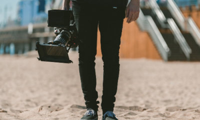 lower half of a man's body dressed in black and carrying a video camera