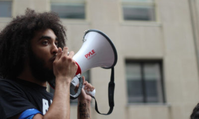 curly haired man speaking through a megaphone