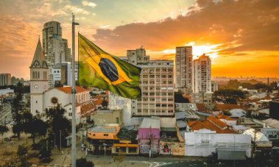 cityscape at sunset with prominent Brazil flag in the foreground