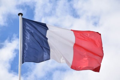 French flag on a mast against a blue sky and white clouds