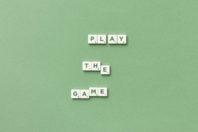 Lettered tiles on a moss green backdrop, spelling PLAY THE GAME