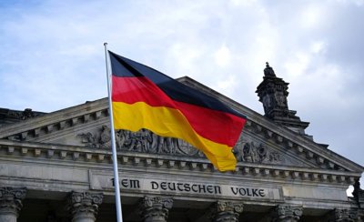 The German flags billows in front of a government building