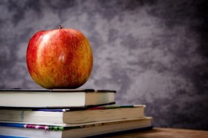 A red apple sits on top of a pile of books